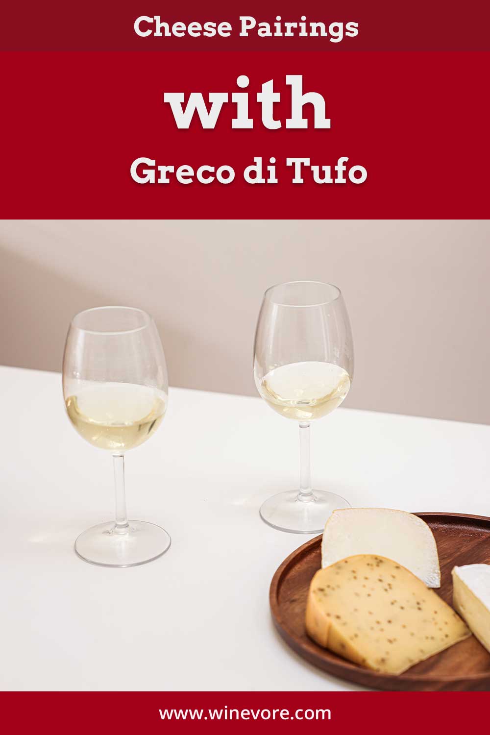 Two glasses of wine with some cheese on a white table - Cheese Pairings with Greco di Tufo.