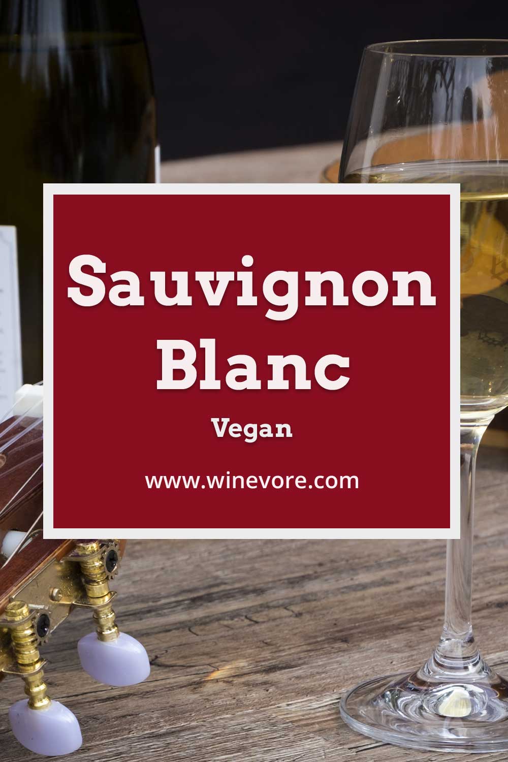 A glass of white wine put on a wooden surface,in front of a guitar and wine bottle - Sauvignon Blanc Vegan.